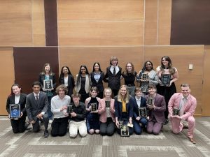 Students in the Northwest Speech and Debate Team holding trophies.