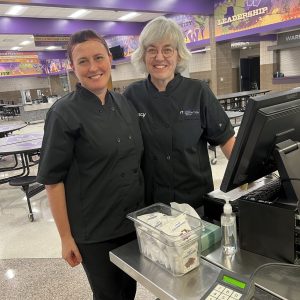 Two nutrition workers standing together and smiling at Waukee High School
