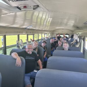 Image of bus driver with high school softball players in a school bus.