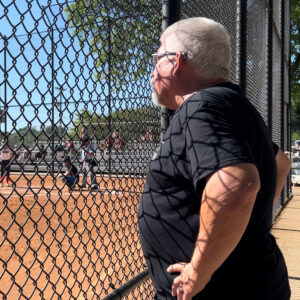 Bus drive Mike Trude watching NWHS softball from the fence.