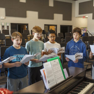 Four students singing at a piano.