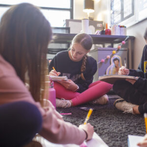 Students sitting on the ground doing classroom work.