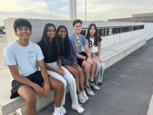 Five students sitting on a bench outside Northwest High School. Those pictured are National Merit semifinalists.