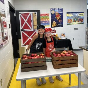 Two students serving apples.