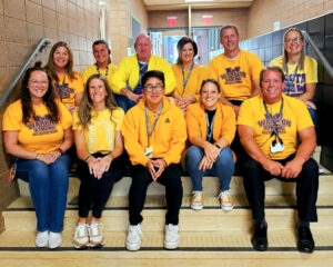 Staff sit on stairs wearing yellow clothes