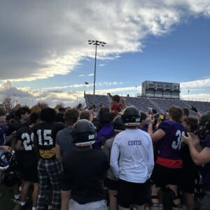 Major hoisted into the air by football players.