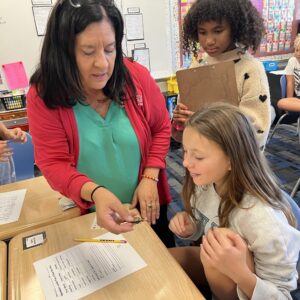 A student tagging a monarch butterfly with a little sticker before release.