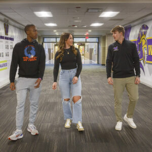 Three students talking in the hallway.