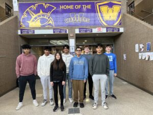 Group of students standing in the hallway smiling for a photo.