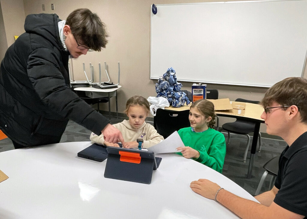 High school students help two younger students with iPad