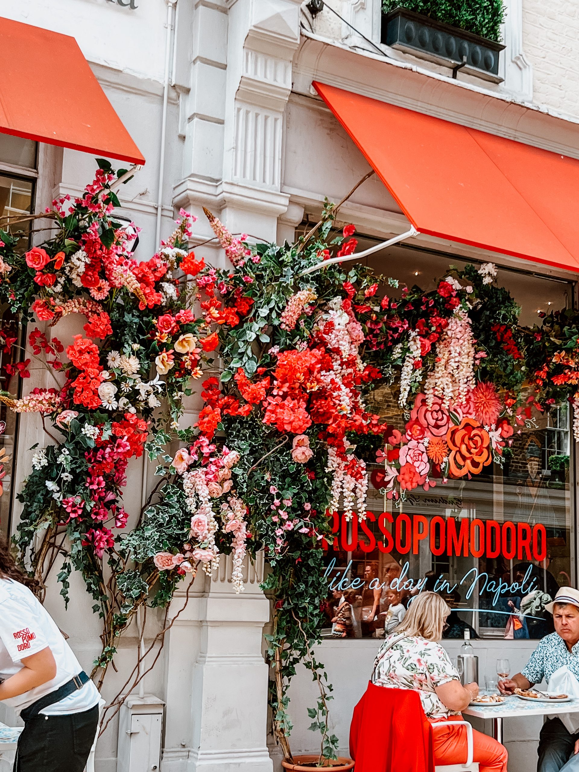 Vines with flowers grow on a cafe. 